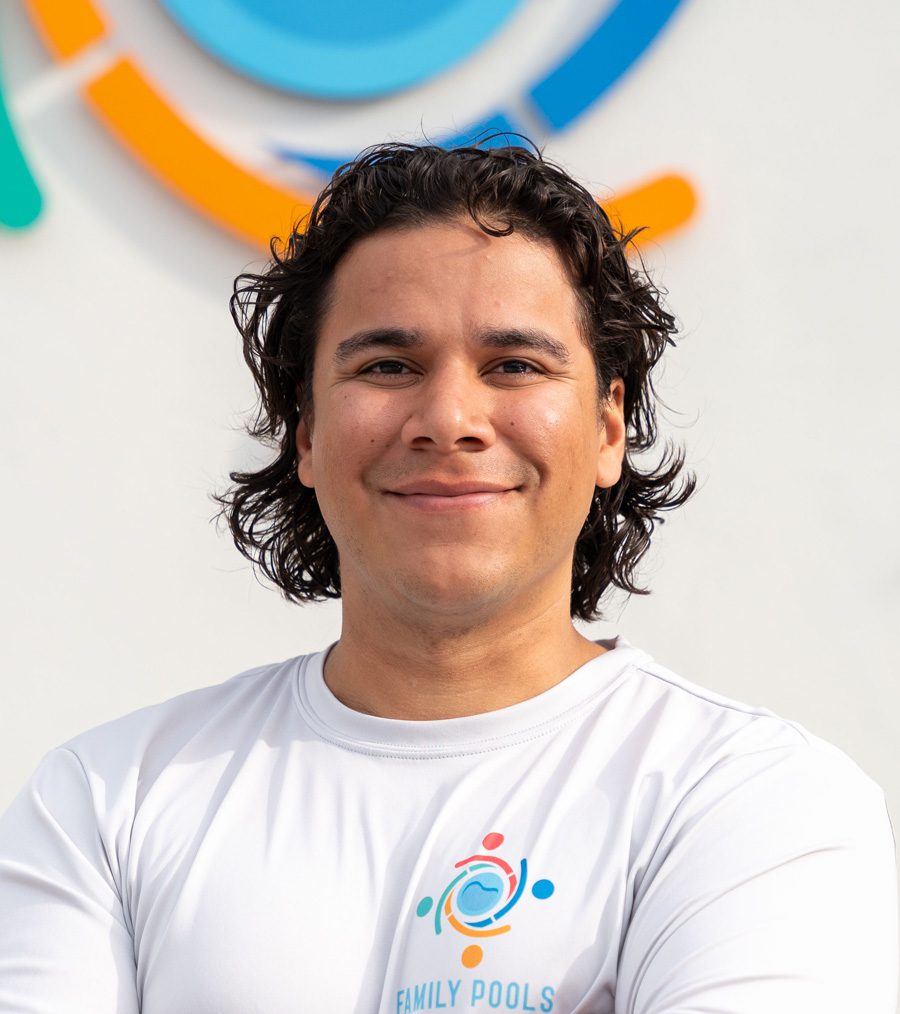 Young man smiling in a white shirt with "Family Pools" logo, standing in front of a colorful background, representing the team at Florida Family Pools.
