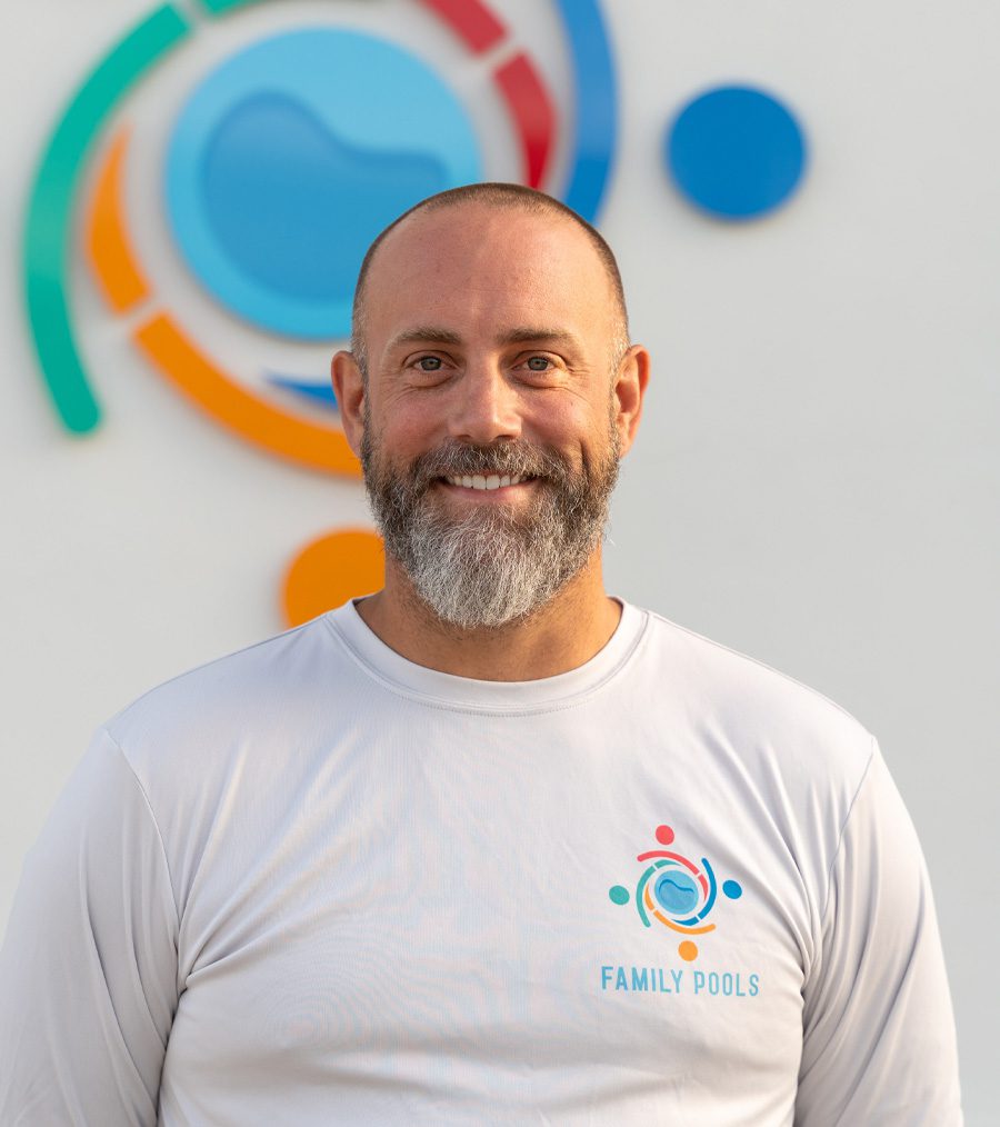 Man smiling in a white shirt with "FAMILY POOLS" logo, standing in front of a colorful abstract design, representing Florida Family Pools team expertise in custom pool construction.
