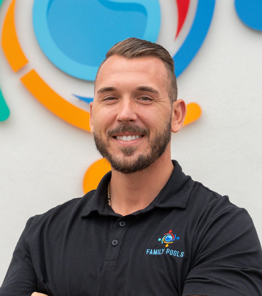 Zach Anadio, Sales Advisor at Florida Family Pools, smiling in front of a colorful logo backdrop, wearing a black polo shirt with "FAMILY POOLS" branding.